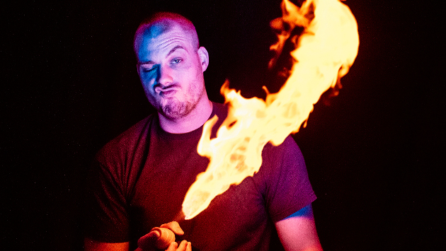 Der Künstler POK im dunkeln mit einer Flamme neben sich.
