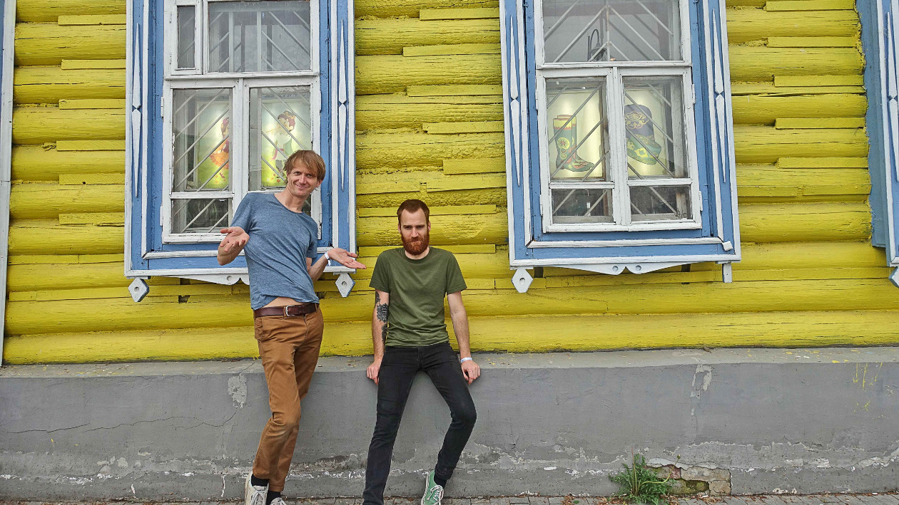 Die Künstler "La Jungle" stehen vor einer gelben Hauswand, das Haus hat blaue Fensterläden.