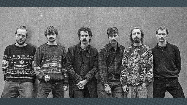 Eine schwarz weiß Aufnahme der Band Lovemachine, alle Mitglieder stehen nebeneinander vor einer Wand.