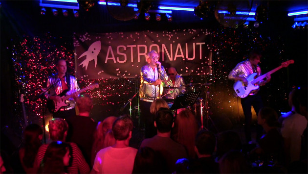 Die band Astronaut spielt auf einer Bühne, man sieht die vorderste Reihe Zuschauer.