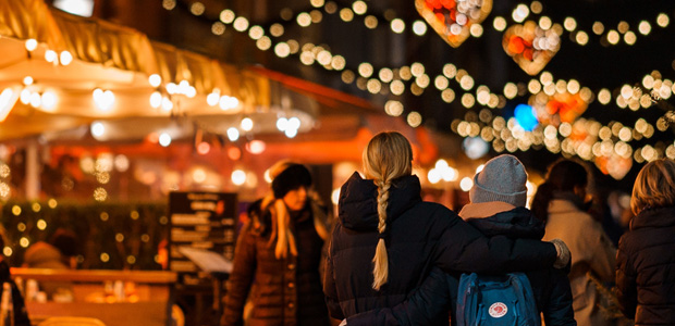 Menschen gehen abends durch eine weihnachtlich dekorierte Innenstadt